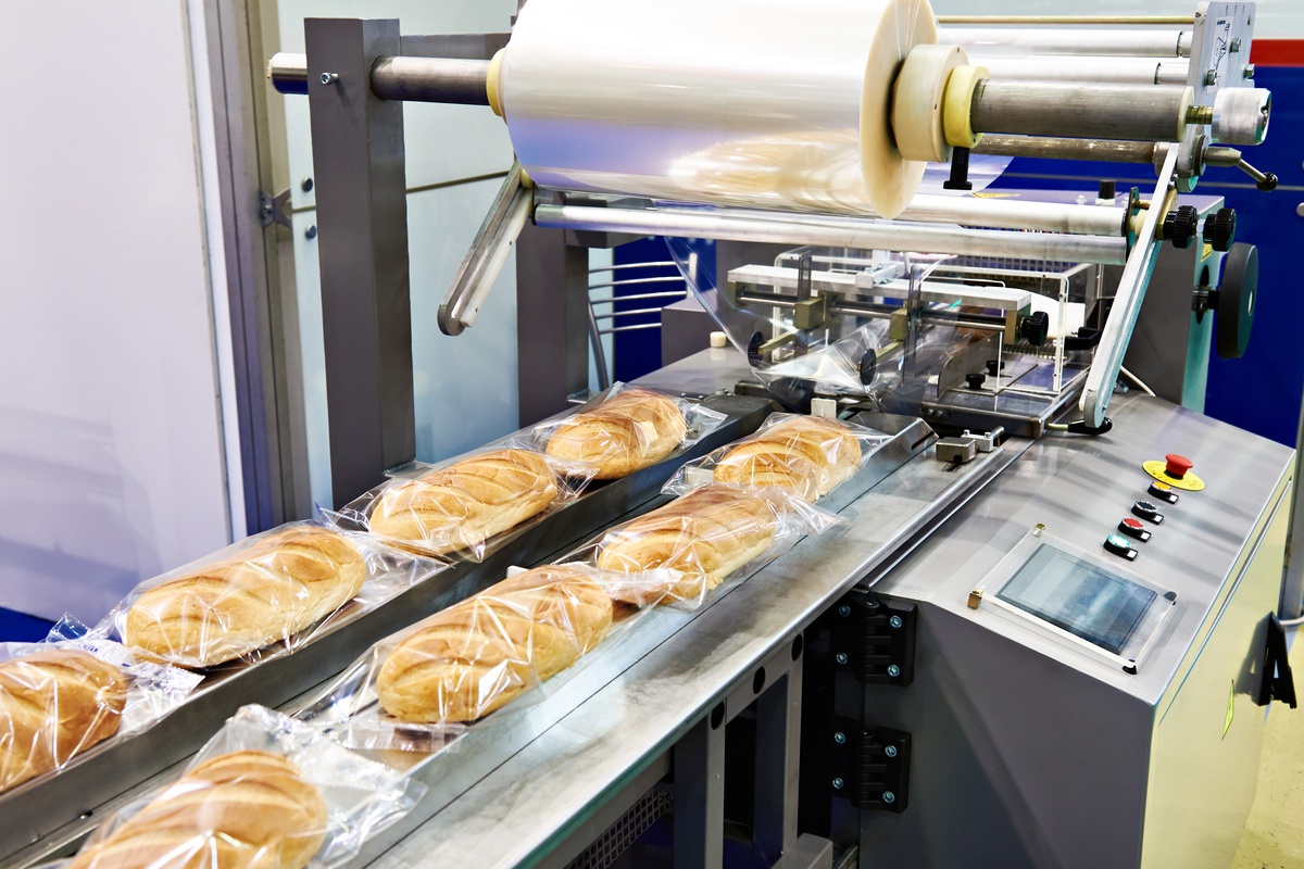 Bread packaged in plastic on a conveyor. The conveyor belt is metal, and there are buttons next to it.