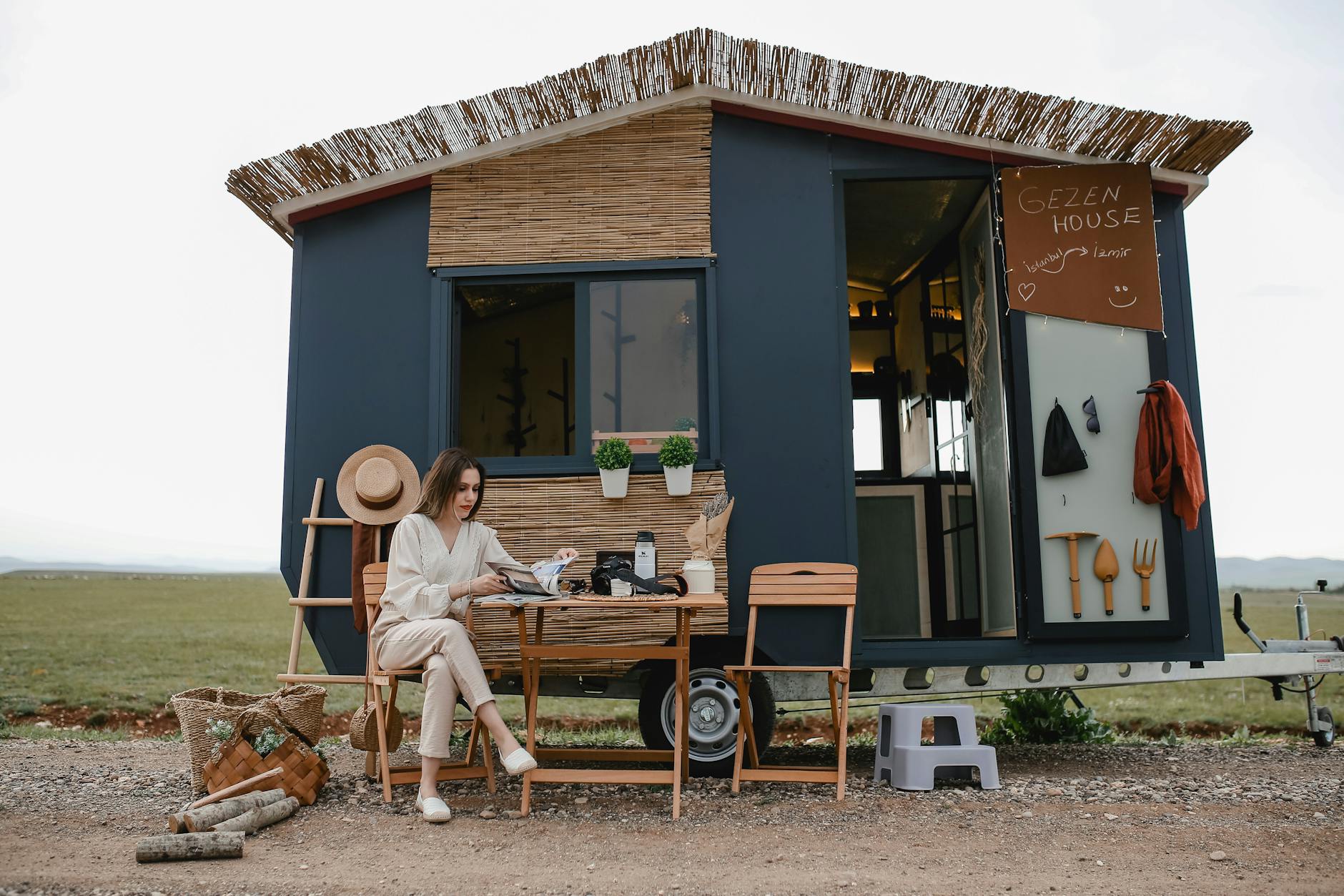 woman sitting in front of a trailer converted to a house on wheels