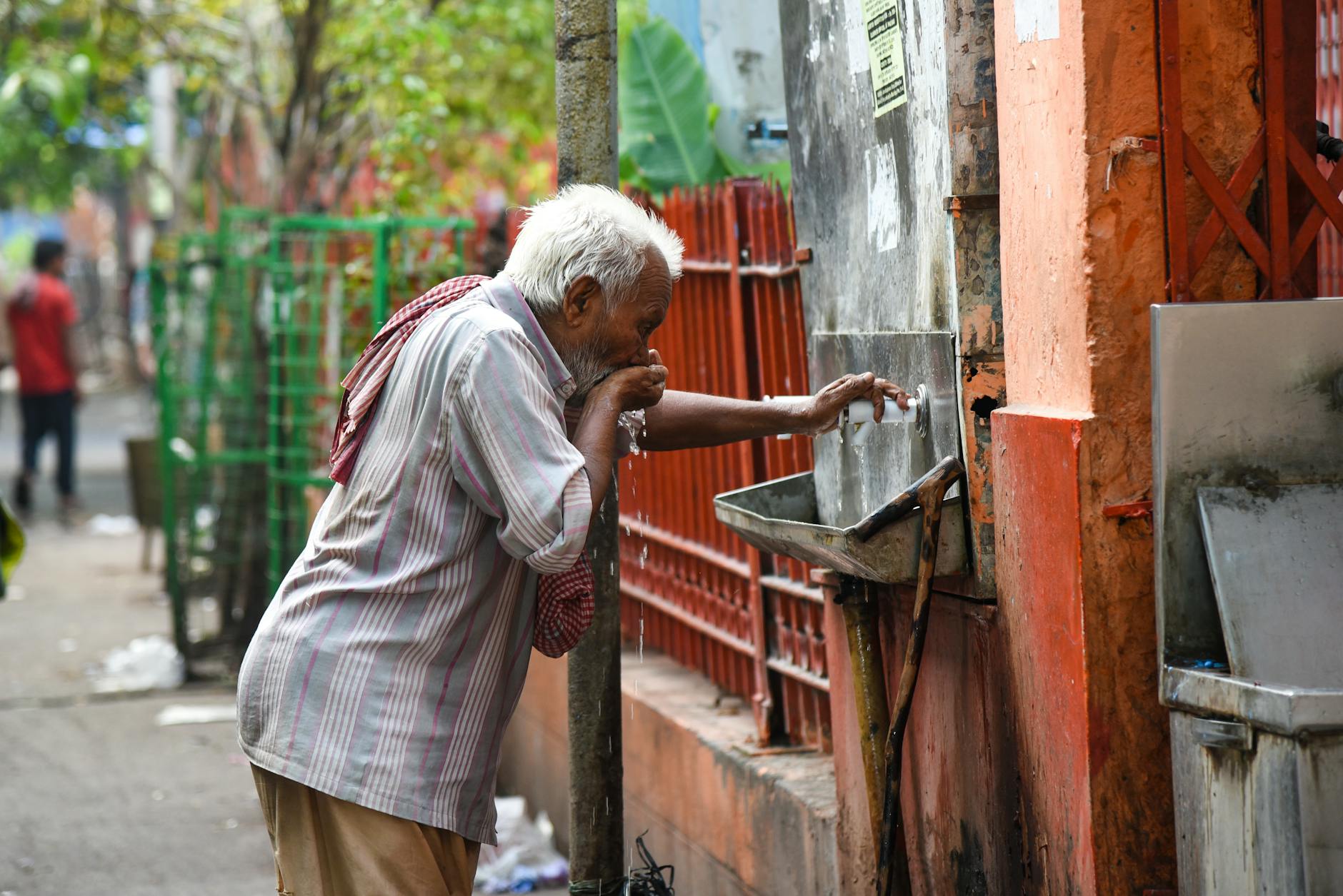 man drinking water from drinking fountain