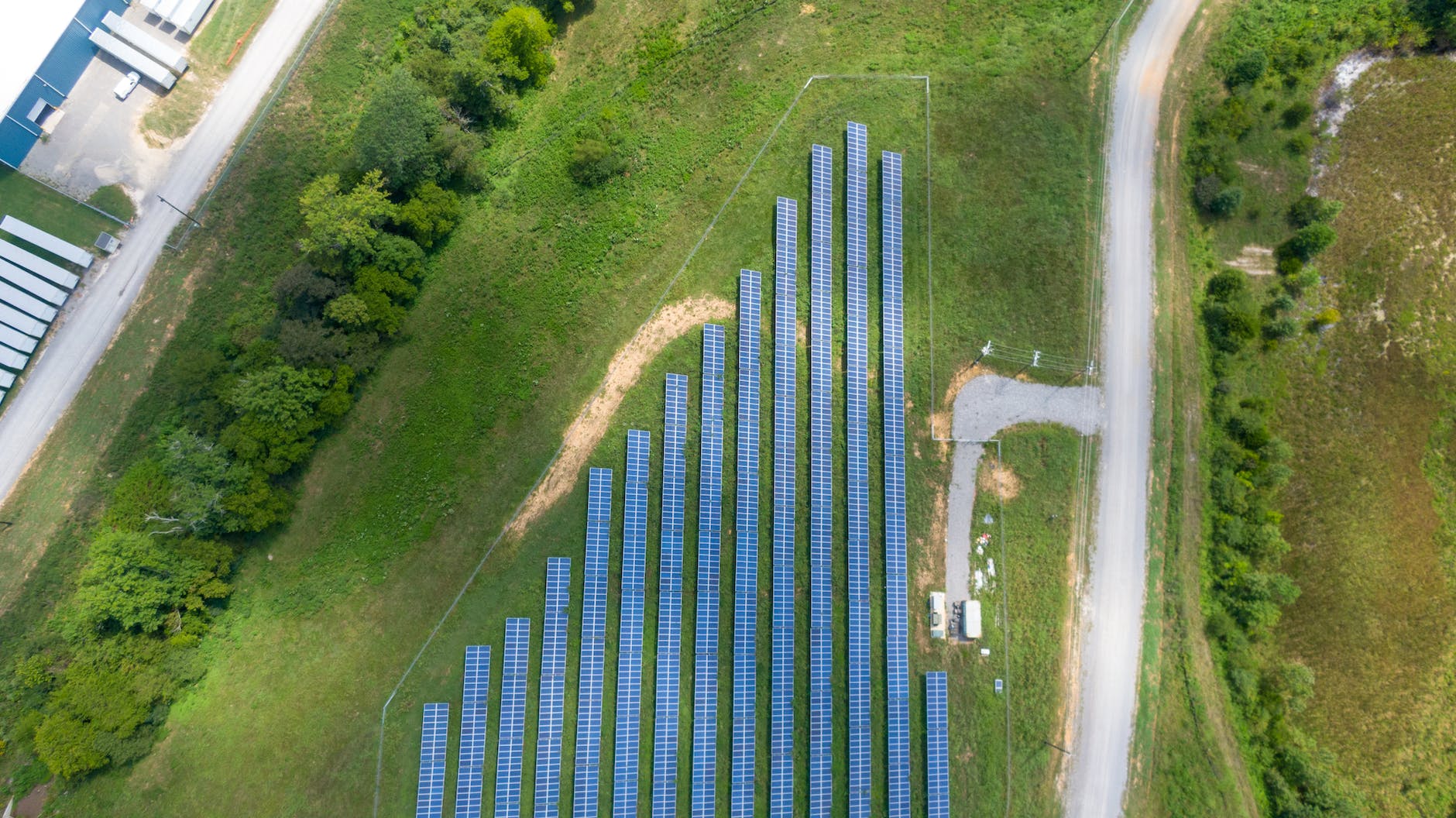 aerial view of solar panels array on green grass