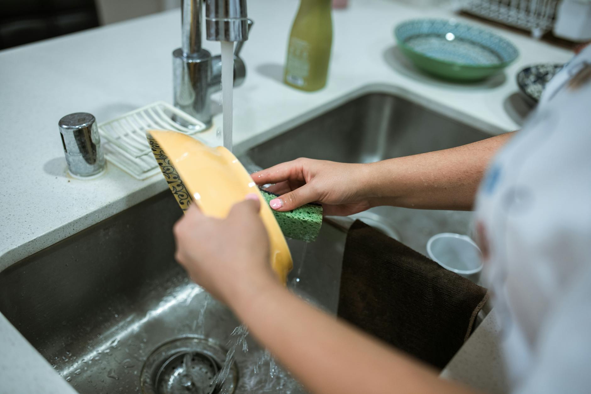 a person cleaning a yellow bowl using a sponge