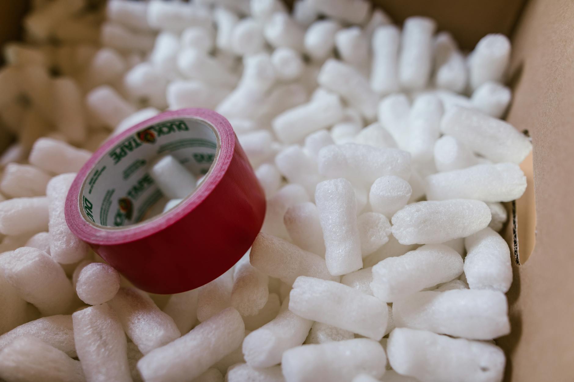 red duct tape and packing peanuts inside a carton box