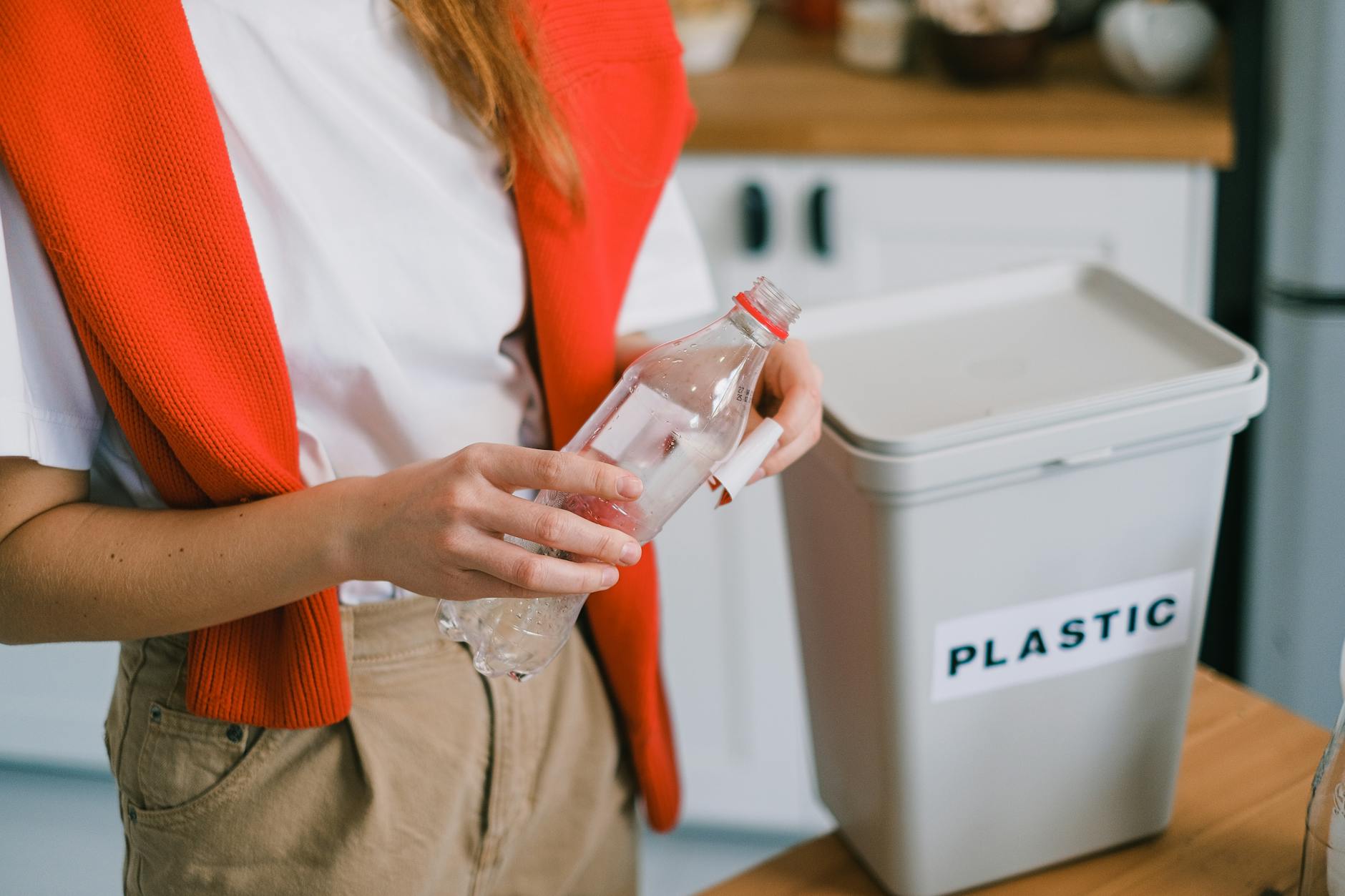 person holding a plastic bottle near a bucket