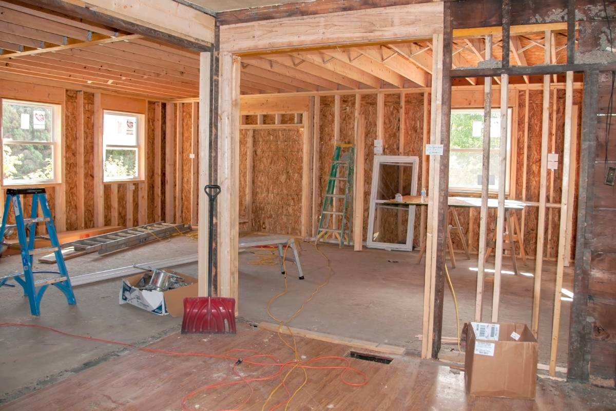 The interior of a home under renovation with bare interior walls lacking insulation and tools on the floor.
